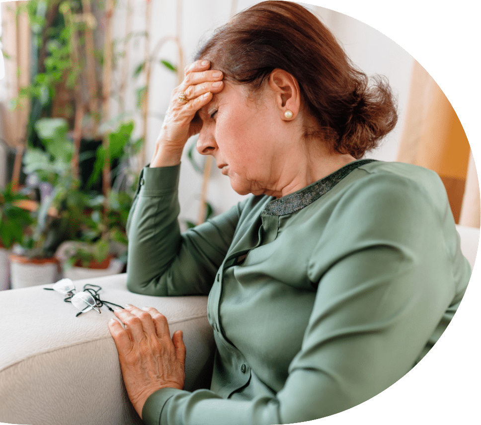 older woman sitting on her couch while feeling ill and suffering from pneumonia in seniors