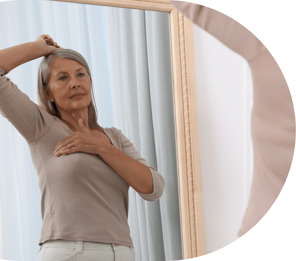 Woman with signs of breast cancer examining herself in the mirror