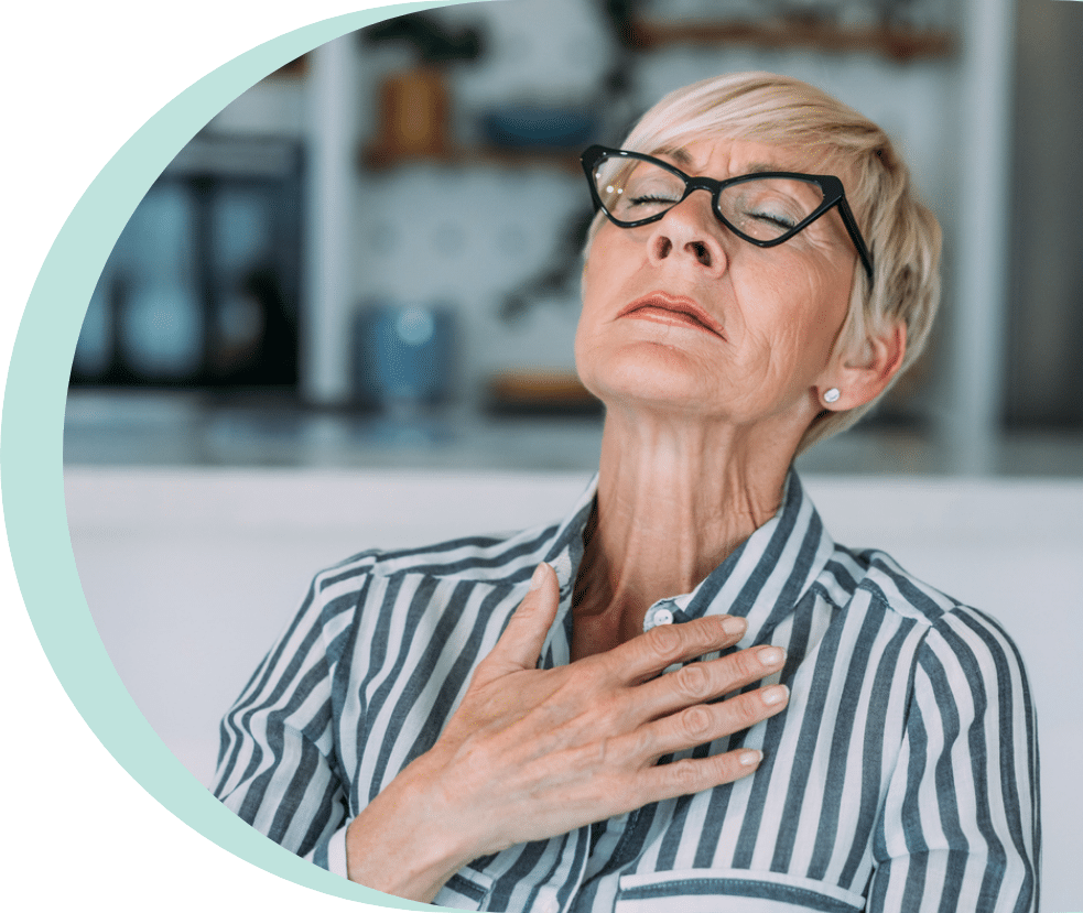 Older woman sitting on the couch holding her heart due to AFib in seniors