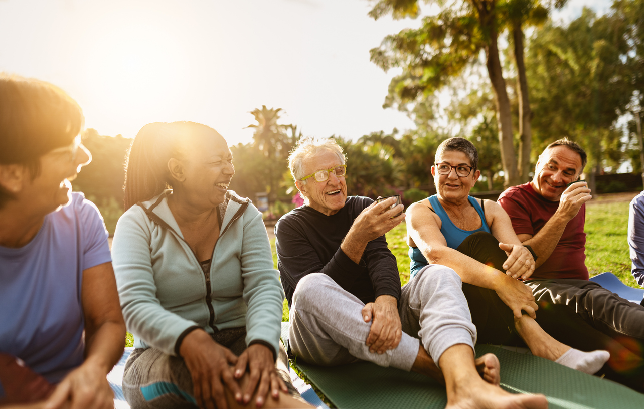 Happy multiracial senior friends drinking a tea after workout activities in a park